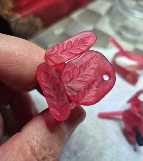 Red leaf-shaped lost wax sculpting held by a hand with a blurred background