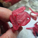 Red leaf-shaped lost wax sculpting held by a hand with a blurred background