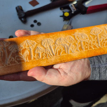 Wooden tool with fungi carvings held by a person, with a blurred background